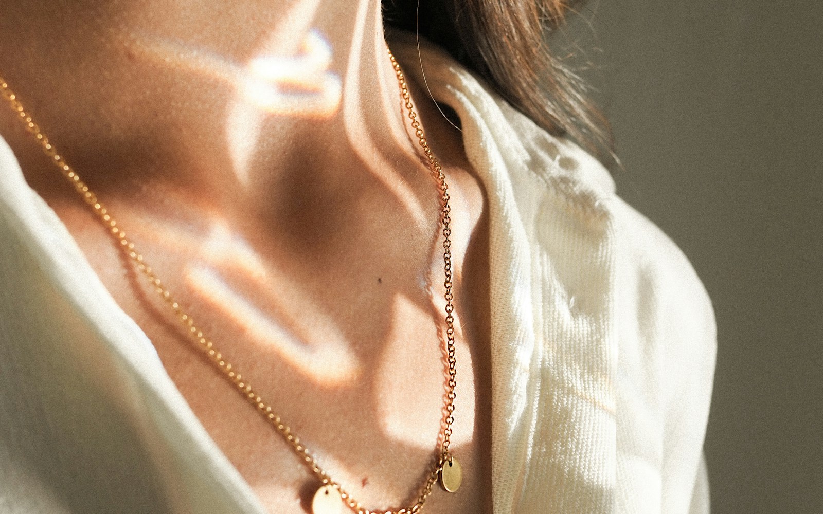 A person fastening a small stud earring in front of a bedroom mirror