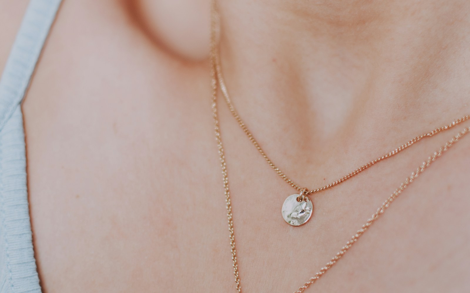 A shopper comparing two simple chain necklace lengths against a neutral top